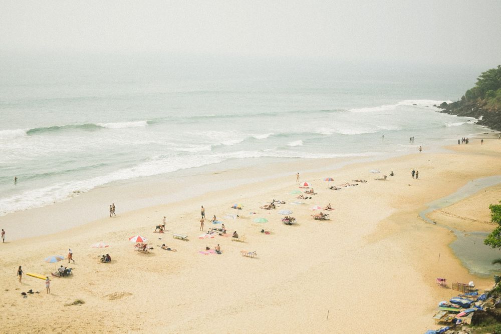 Beachgoers relaxing on a sandy shore with waves rolling in from a misty ocean.