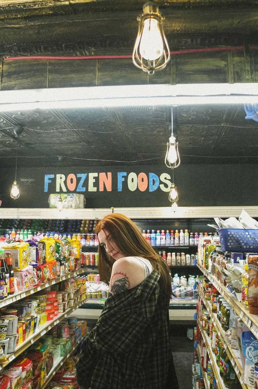 Inside a convenience store's frozen foods section with hanging lights and stocked shelves.