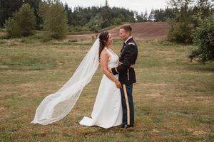 Wedding couple's silhouette against natural landscape with flowing veil in wind.