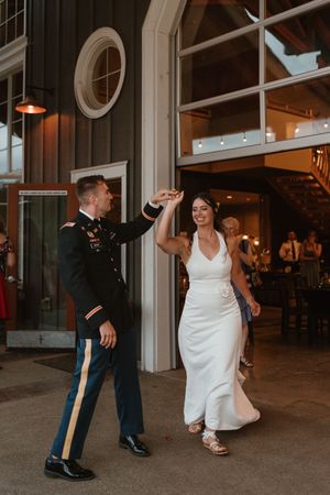 Wedding couple dances together in venue with industrial-style windows and dark walls.