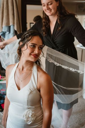 Bride getting dressed in a white wedding gown with delicate veil details.