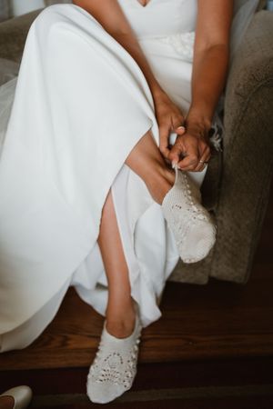 Close-up shot of white lace bridal shoes being put on.