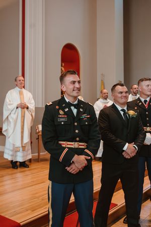 Military groomsmen in dress uniforms stand at attention during wedding ceremony.