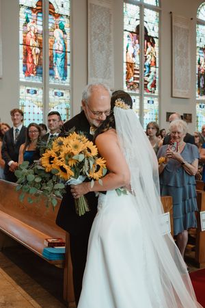 Church wedding ceremony with sunflowers and stained glass windows in background.