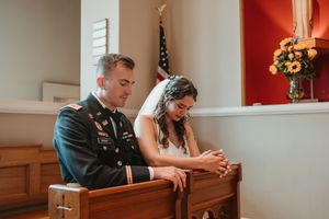 Couple praying together in church pews during a wedding ceremony.
