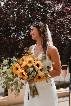 Bride holding vibrant sunflower bouquet with eucalyptus leaves.