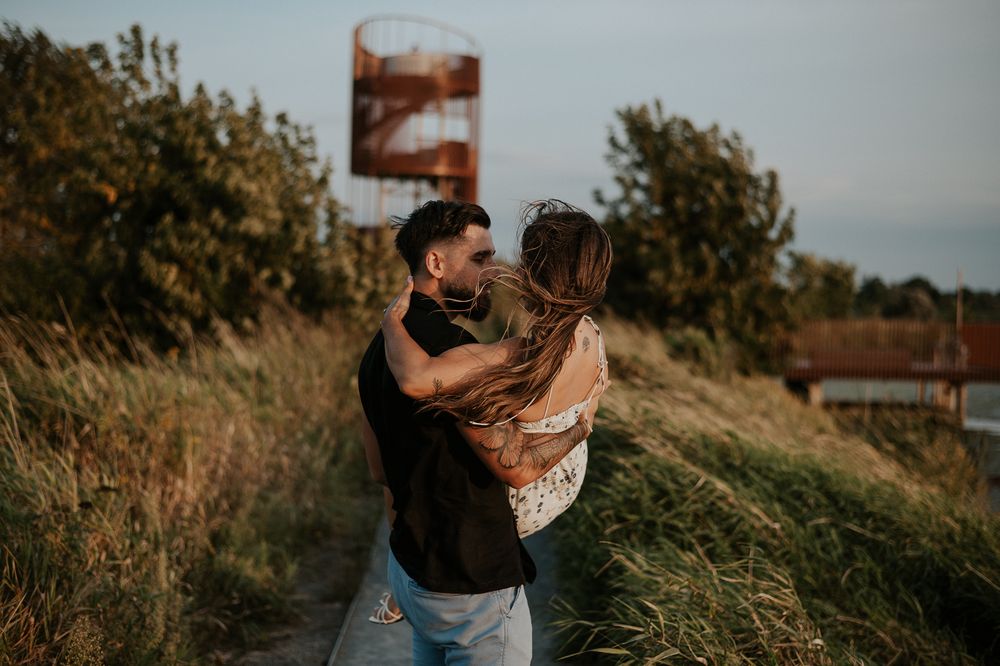 Séance couple en extérieur, deux personnes enlacées dans les herbes hautes, lumière naturelle