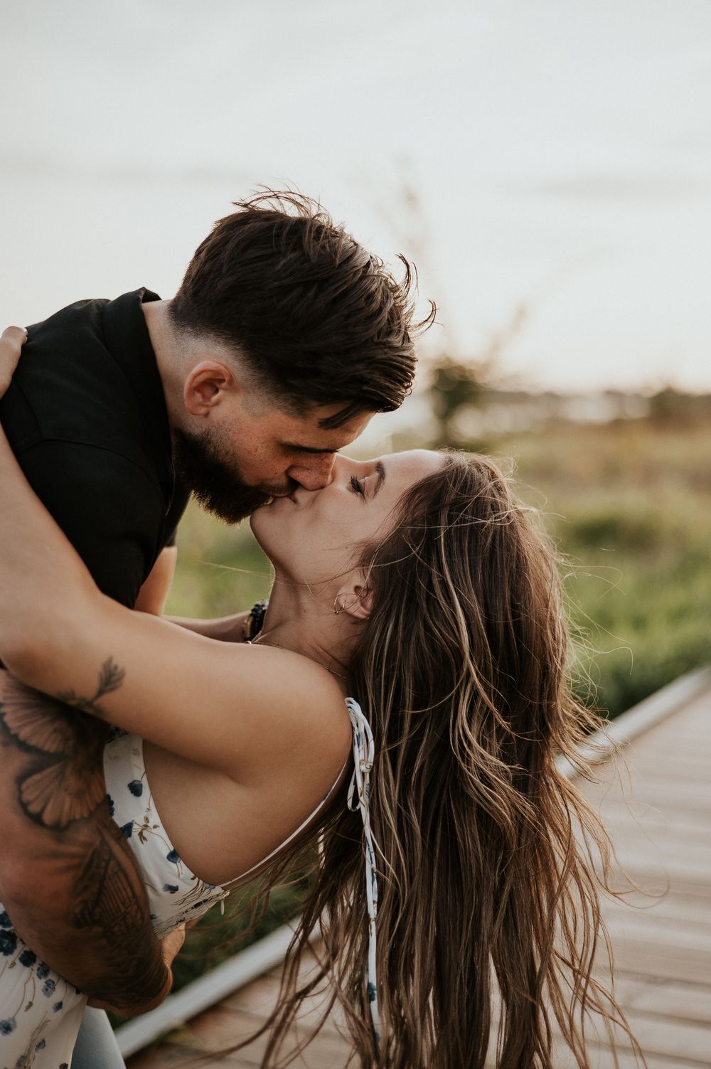 Portrait couple en extérieur, cadrage rapproché près des herbes hautes, lumière naturelle douce