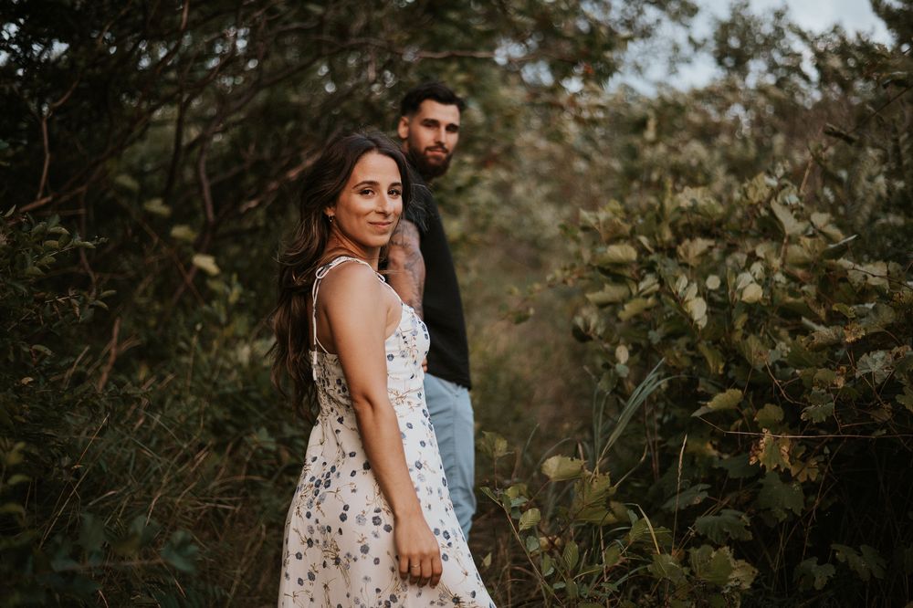 Séance couple en nature, deux personnes debout près des arbres et des herbes hautes