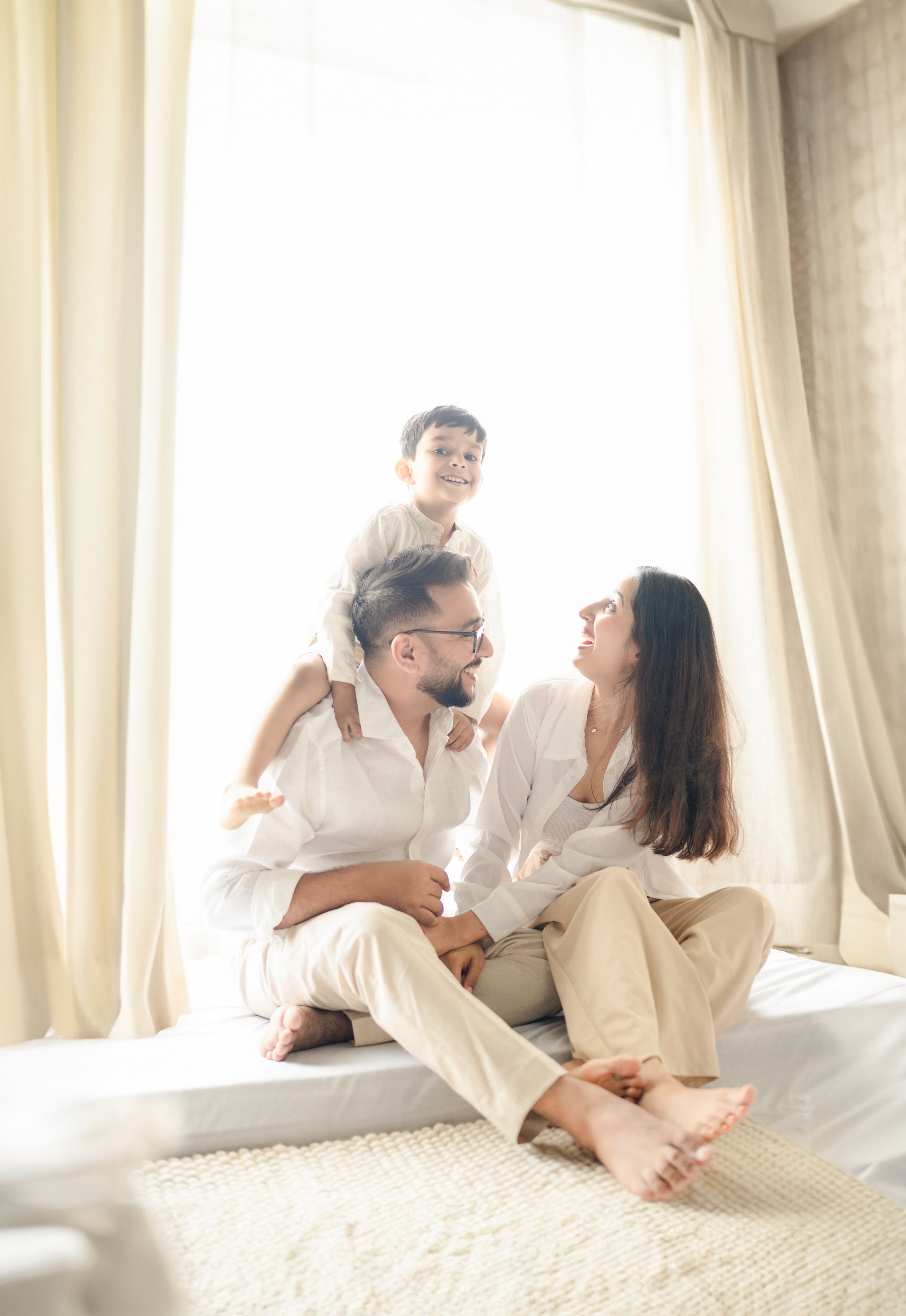 Light-filled indoor family portrait with white decor and natural window lighting.