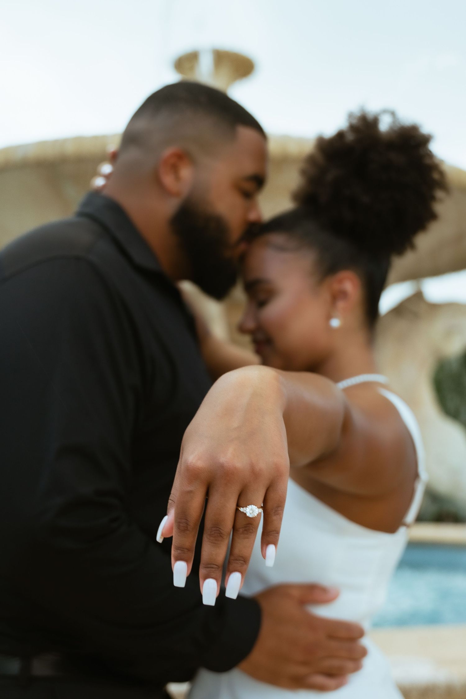 A romantic couple sharing an intimate moment as they lean in close together against a soft blurred background.