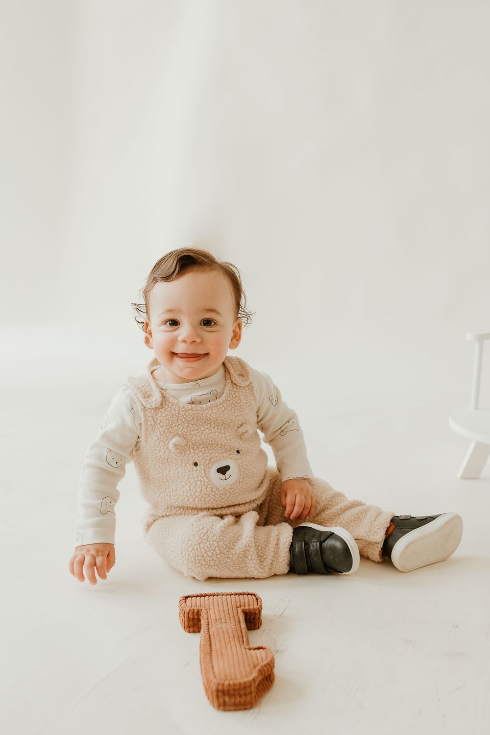 Baby in cozy beige teddy bear vest lies on white background in split-panel progression.