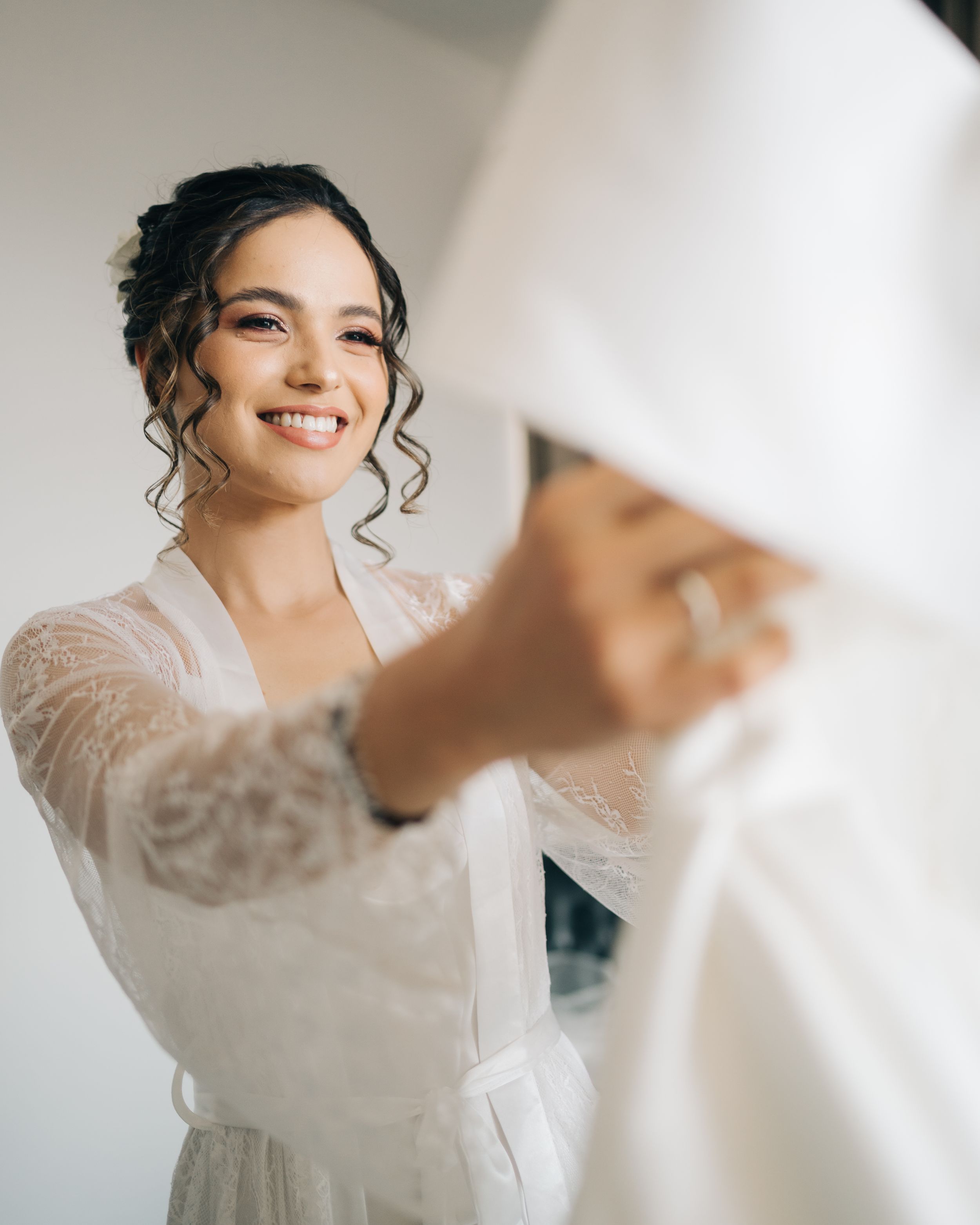 noiva sorrindo enquanto se arruma para o casamento, momento espontâneo do making of da noiva com luz natural