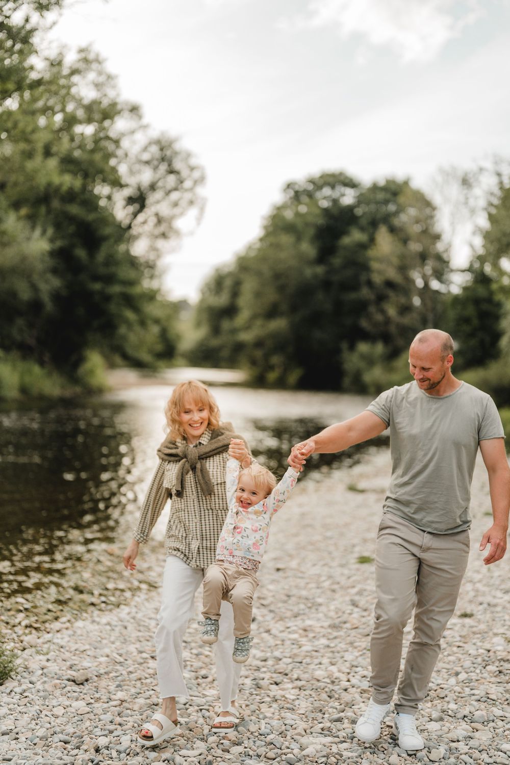 Liebevolle Eltern spielen mit Kleinkind am Wasser bei einem Fotoshooting in Munderkingen. Fotografiert von Ramona Maier