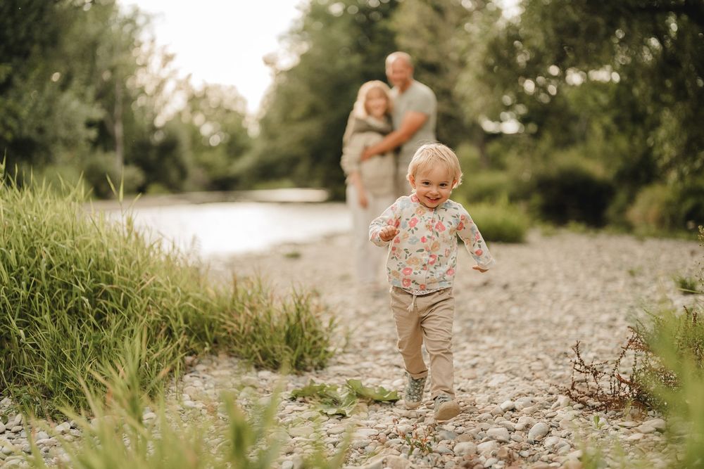 Liebevolle Eltern spielen mit Kleinkind am Wasser bei einem Fotoshooting in Munderkingen. Fotografiert von Ramona Maier
