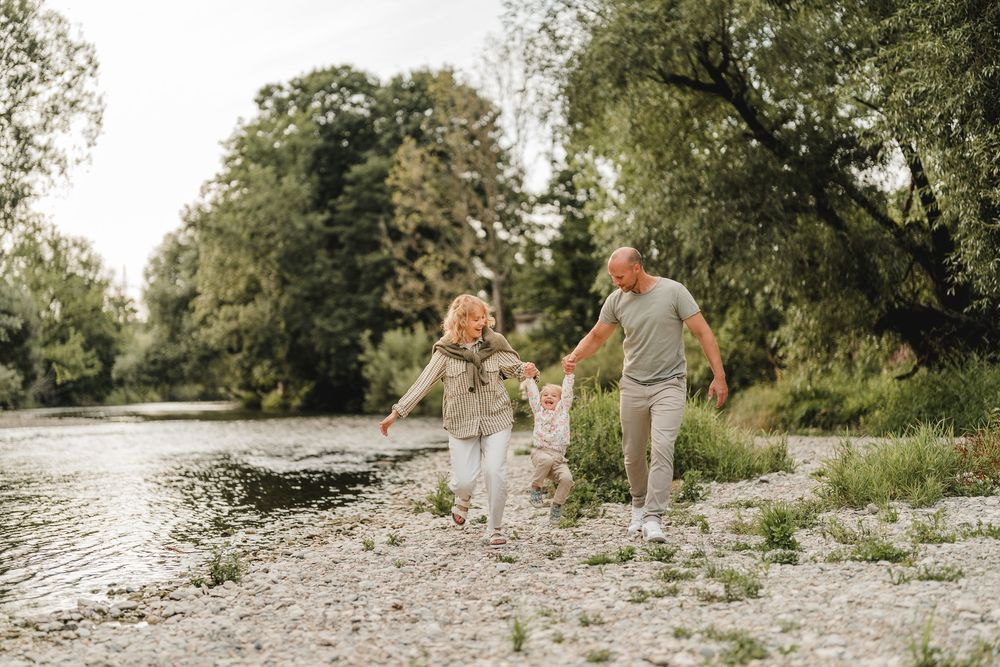 Liebevolle Eltern spielen mit Kleinkind am Wasser bei einem Fotoshooting in Munderkingen. Fotografiert von Ramona Maier