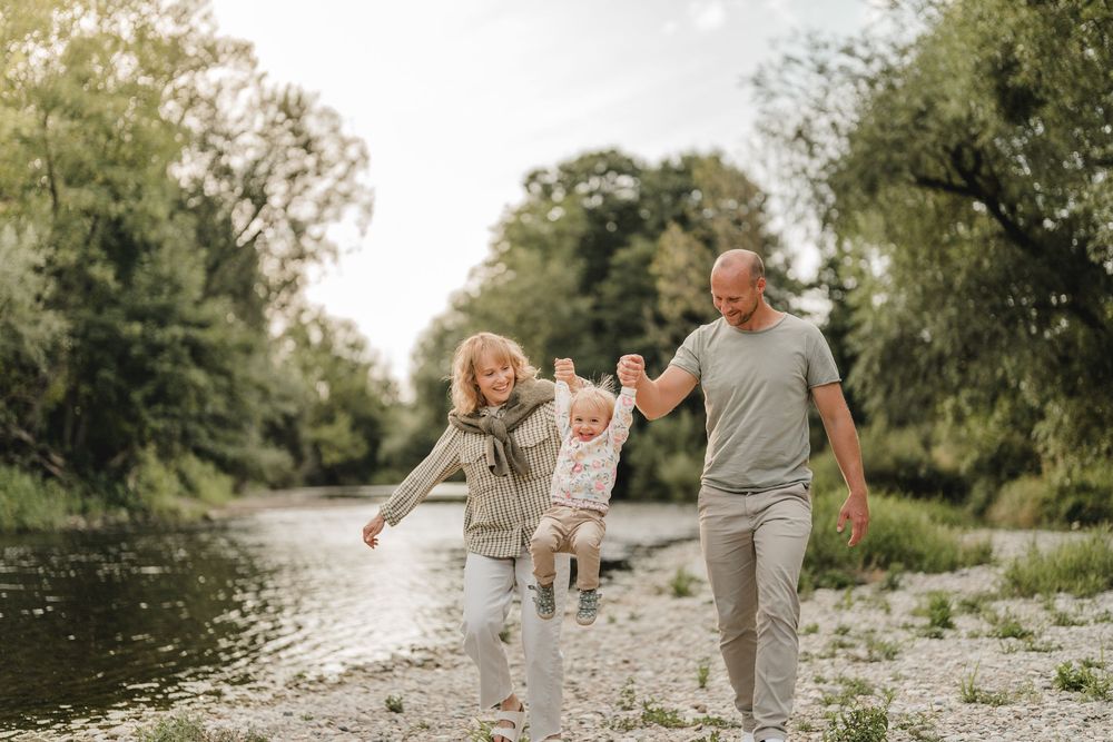 Liebevolle Eltern spielen mit Kleinkind am Wasser bei einem Fotoshooting in Munderkingen. Fotografiert von Ramona Maier