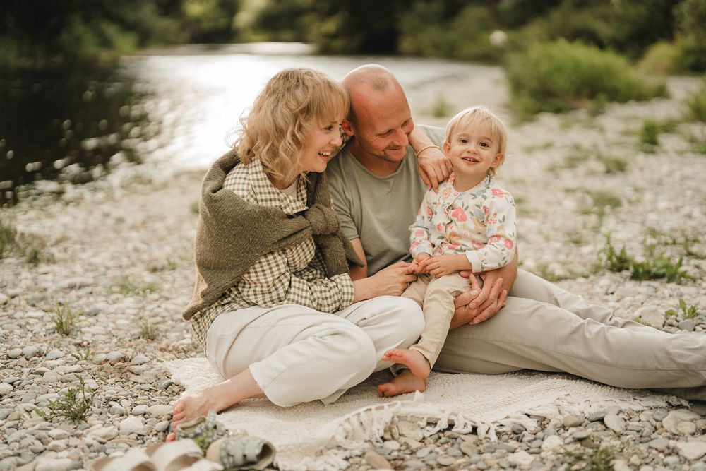 Liebevolle Eltern spielen mit Kleinkind am Wasser bei einem Fotoshooting in Munderkingen. Fotografiert von Ramona Maier