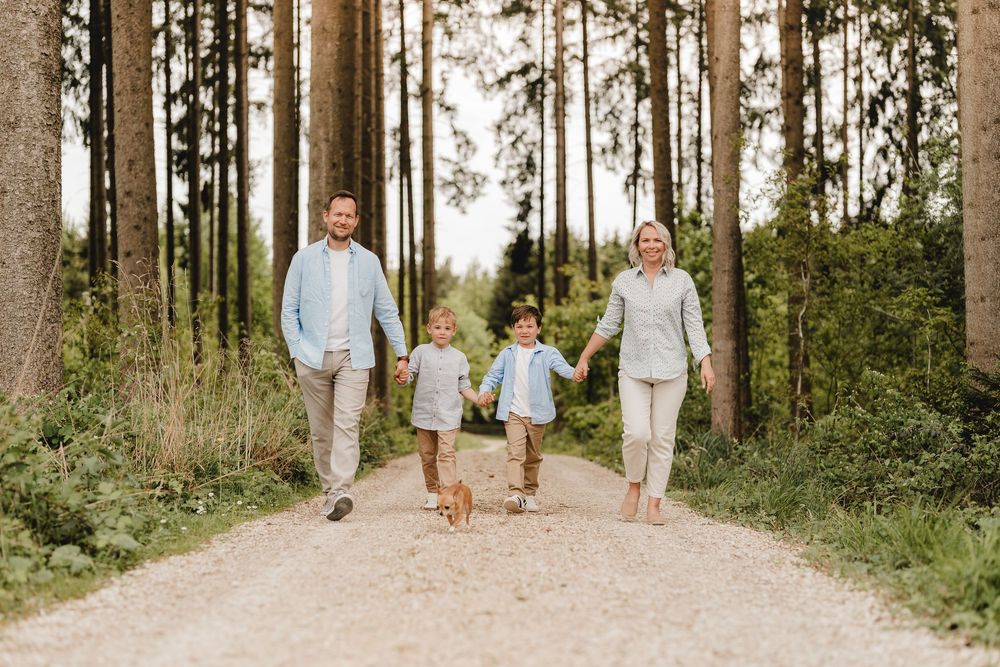 Familie spaziert und spielt gemeinsam auf einem Waldweg an einem sonnigen Tag.