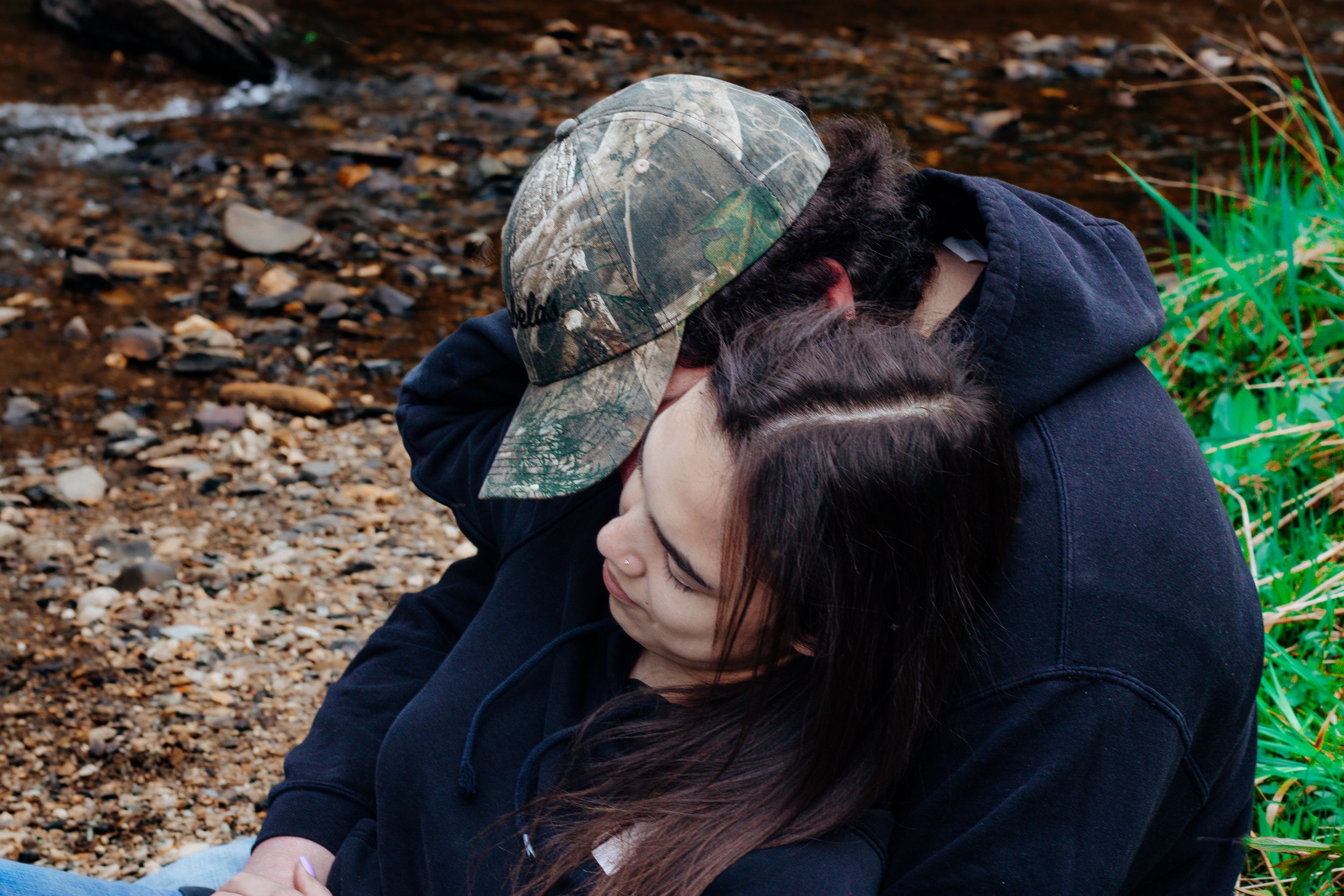A couple sharing a tender moment on forest ground with fallen leaves.
