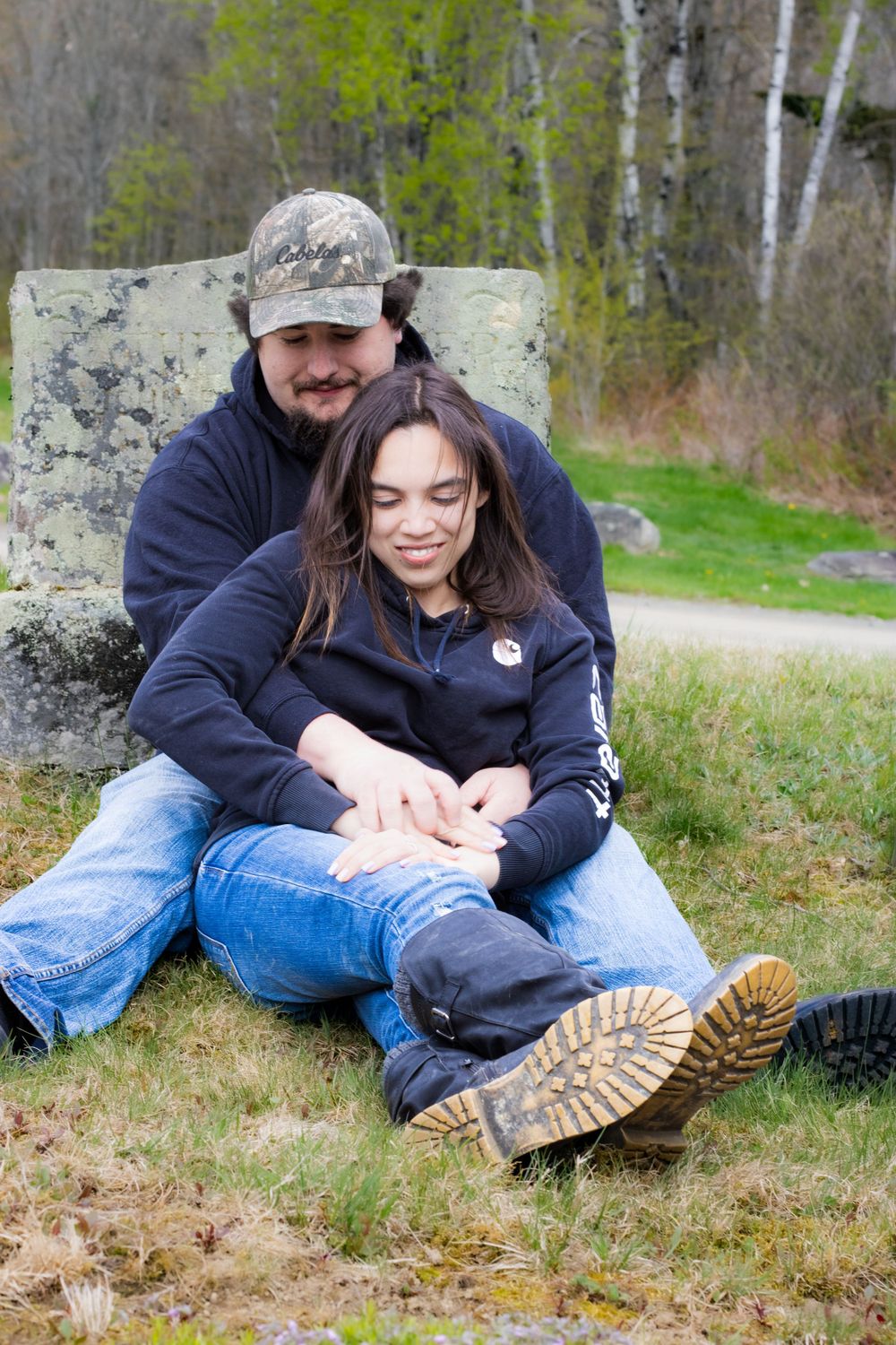 A couple relaxing together on a concrete block surrounded by spring foliage.