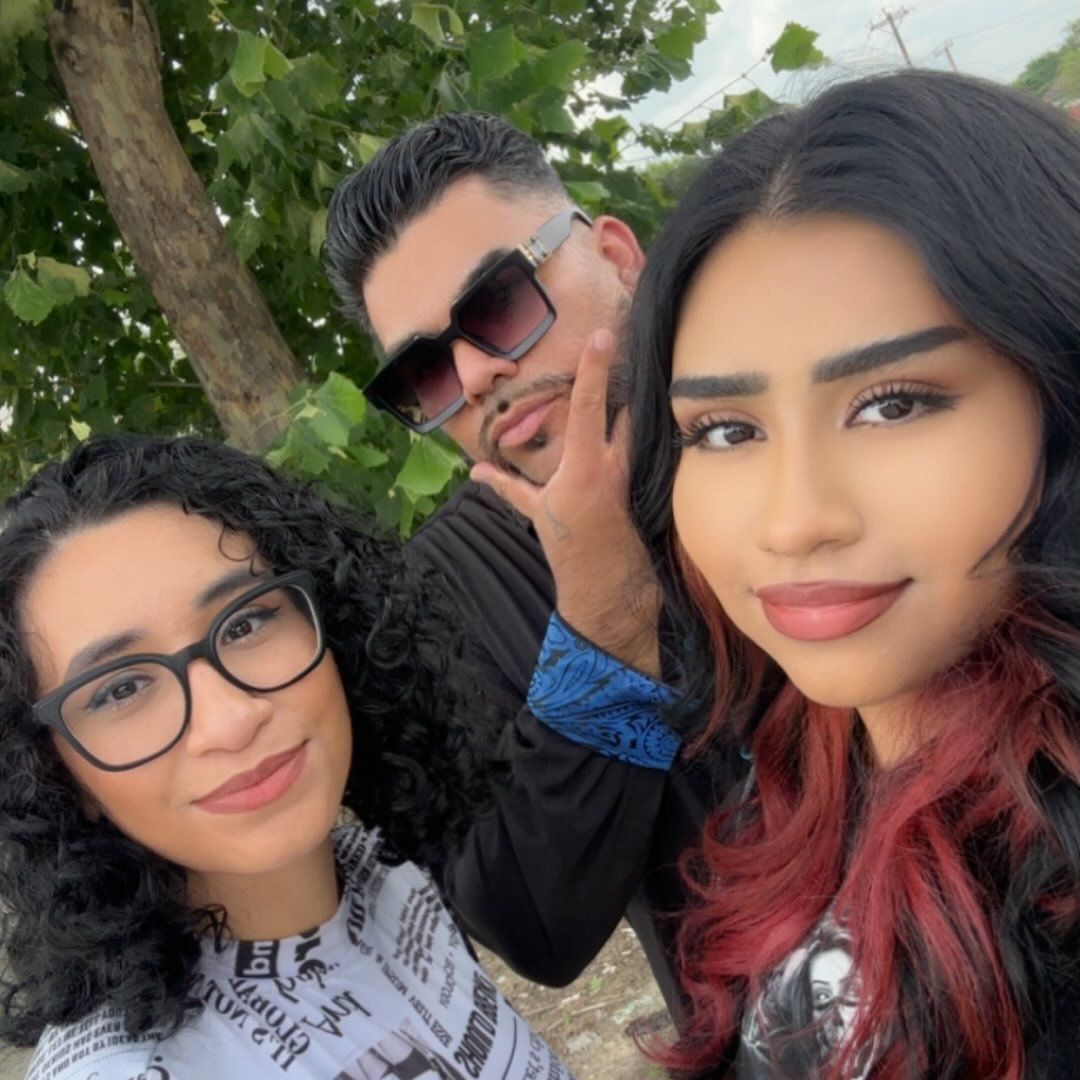 Three people taking a selfie together by a window with a scenic view in the background.