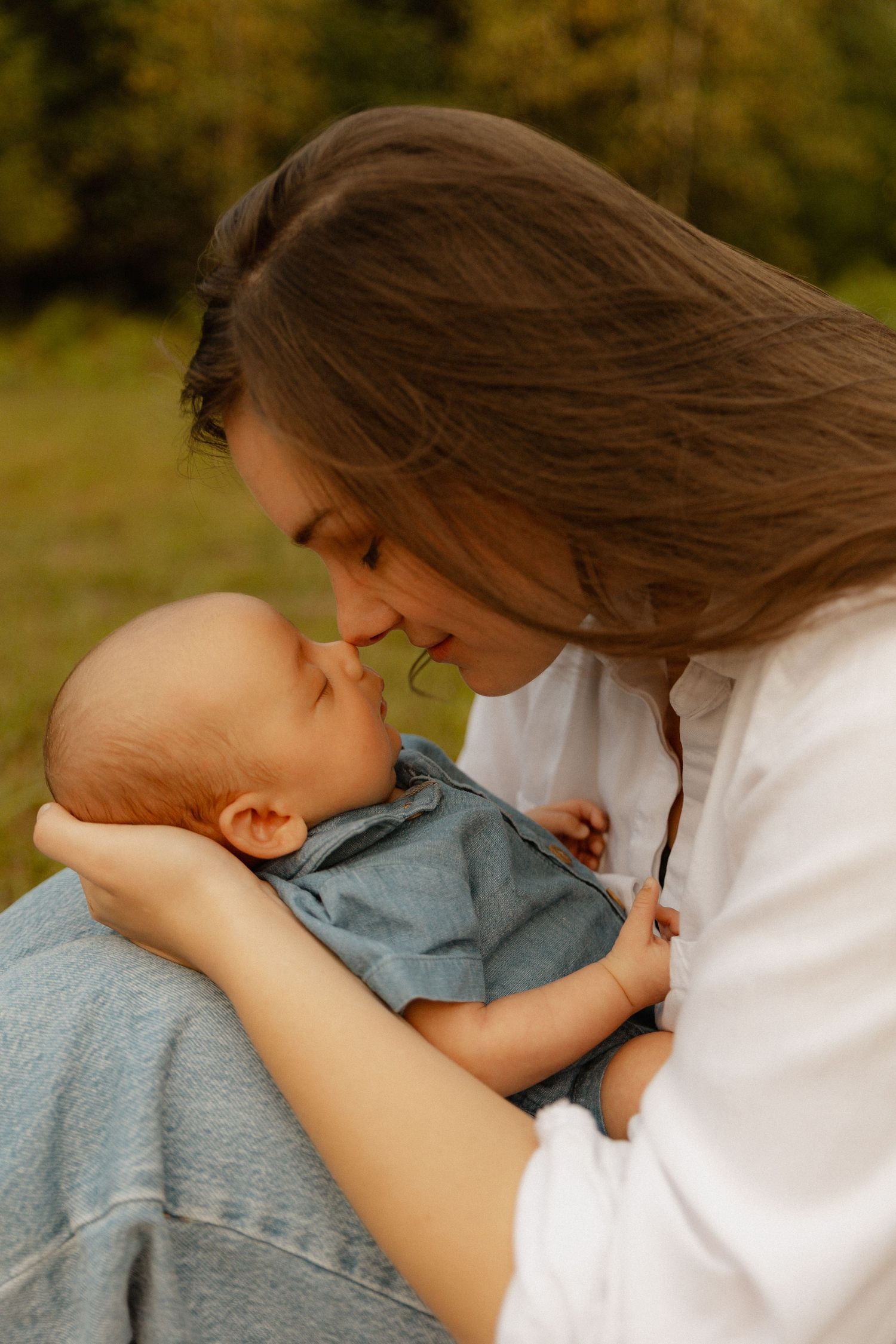 Infant in knit sweater rests peacefully against caregiver in warm, intimate portrait.