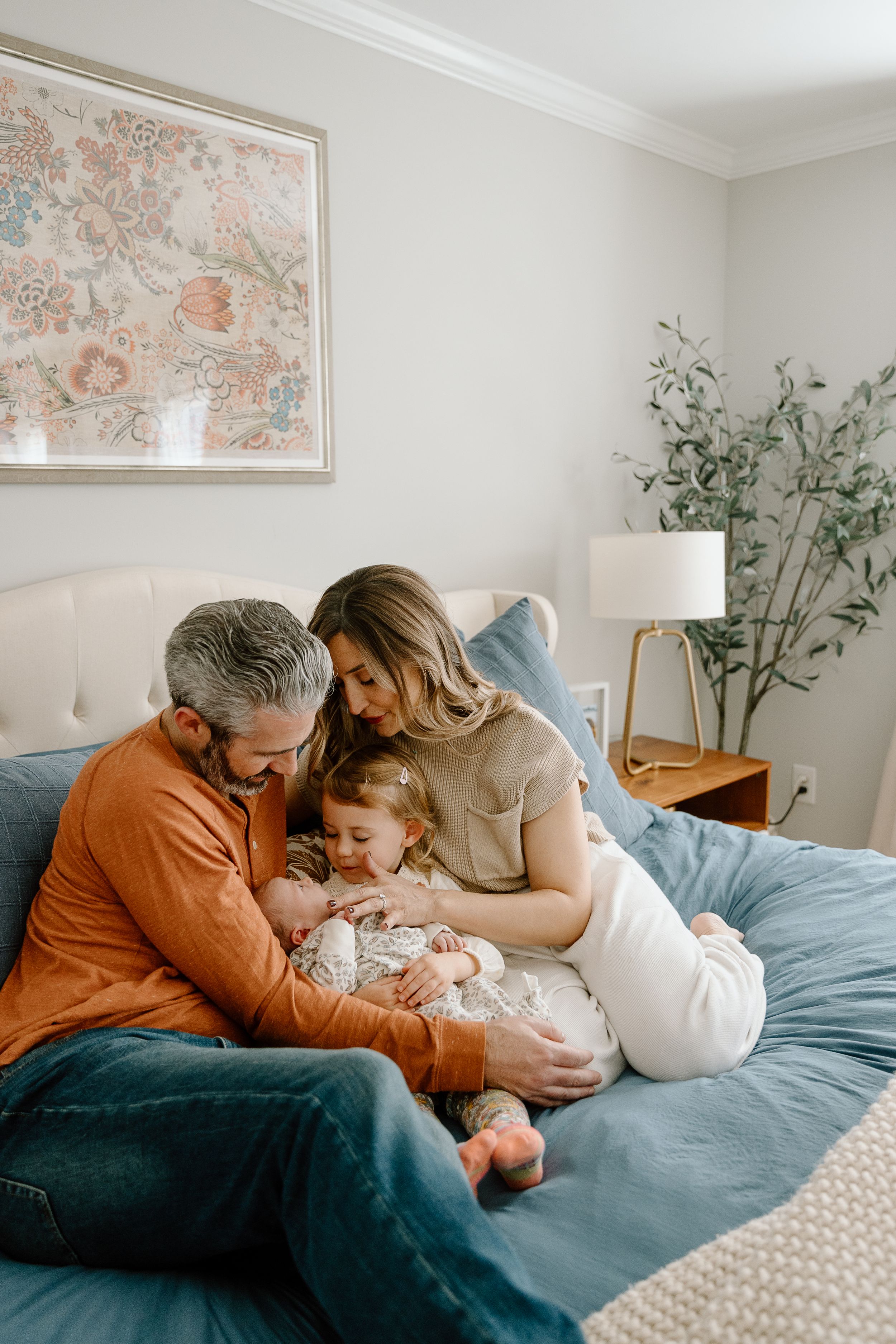 Tender family moment on blue bed with baby in cozy bedroom setting.