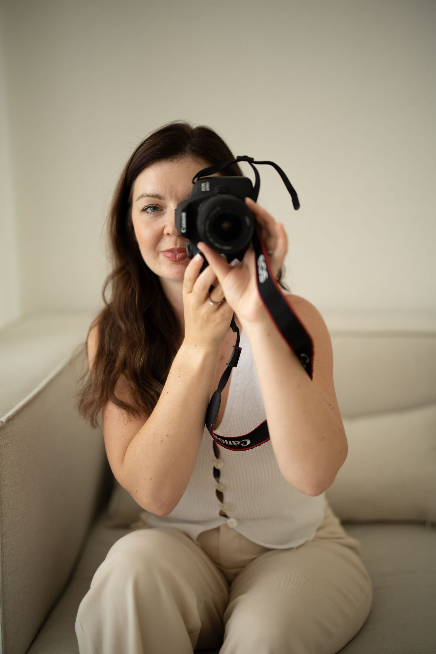 A photographer in white sweater and jeans checks settings on professional camera.