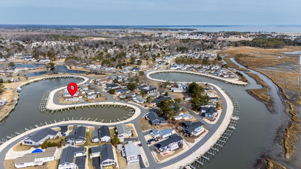 Aerial view of a curved waterfront neighborhood with boat docks and homes along a coastal canal system in Delaware