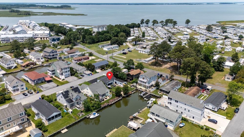 Aerial view of Delaware coastal waterfront homes and boats along a canal in a residential beach community.