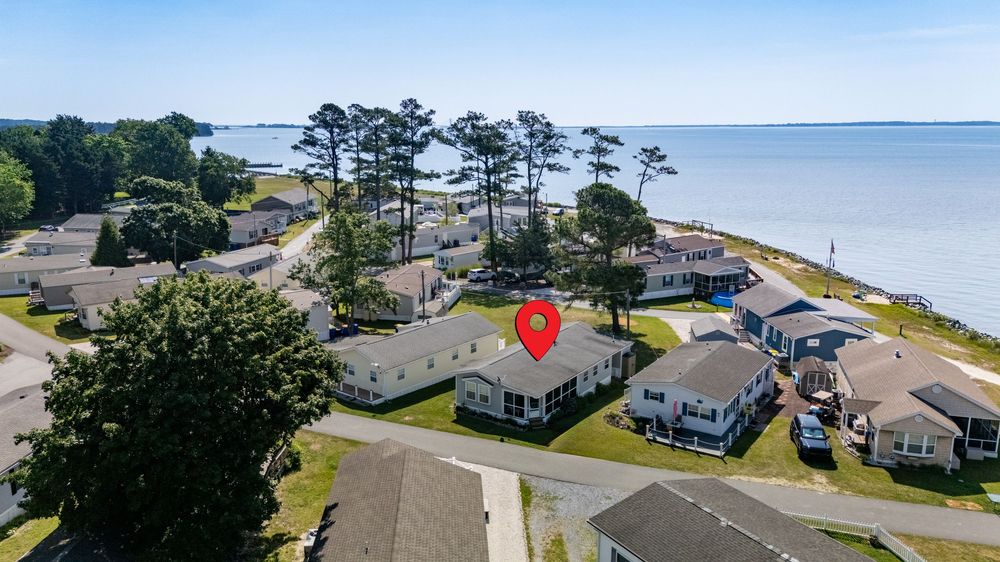 Aerial view of Delaware waterfront vacation homes among pine trees along the Chesapeake Bay coastline.