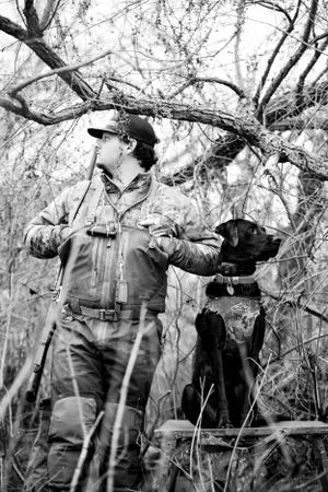Hunters in camouflage gear moving through dense brush during a hunt.