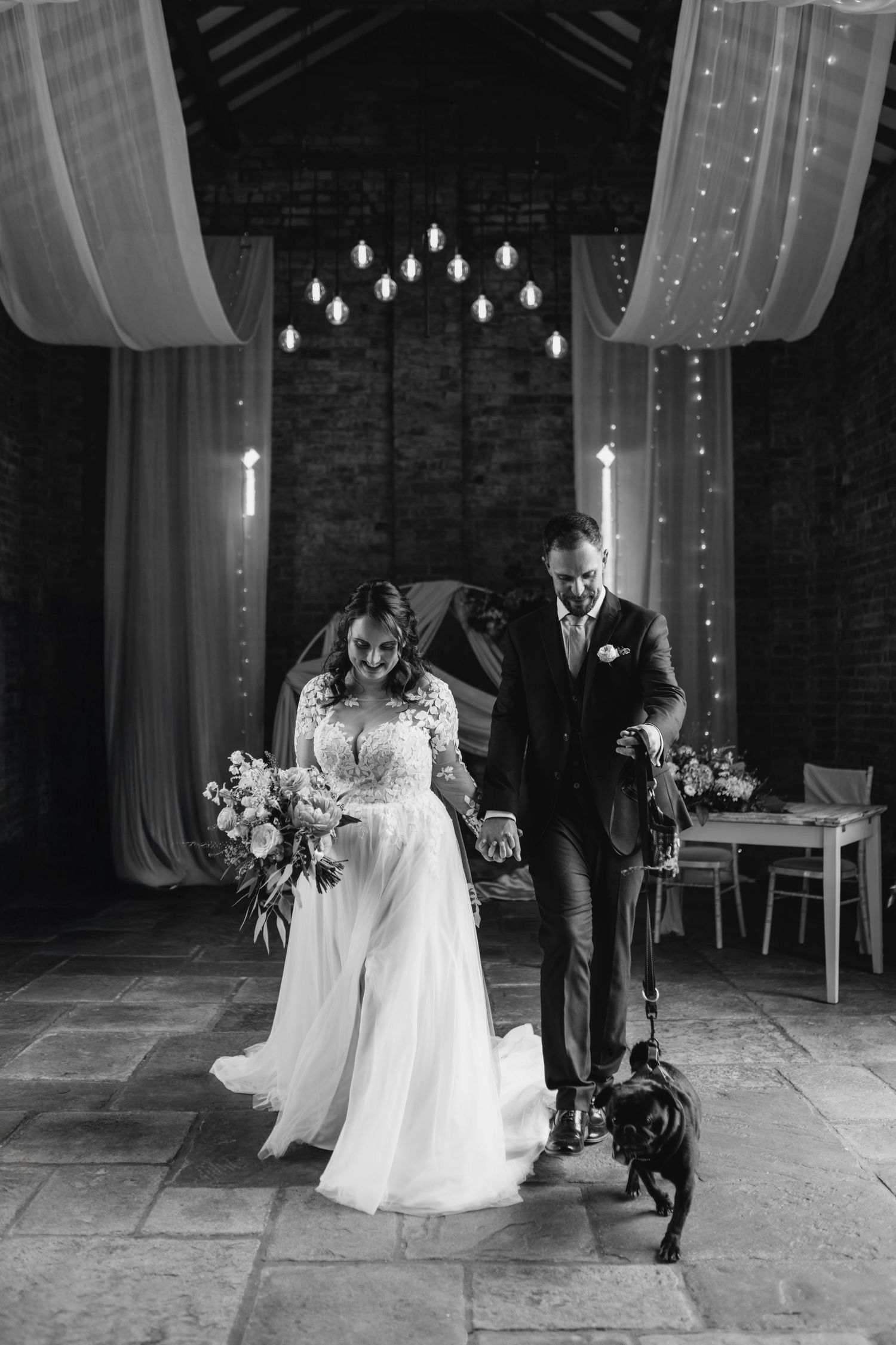 A romantic first dance in a rustic barn venue with exposed stone walls and gathered guests.