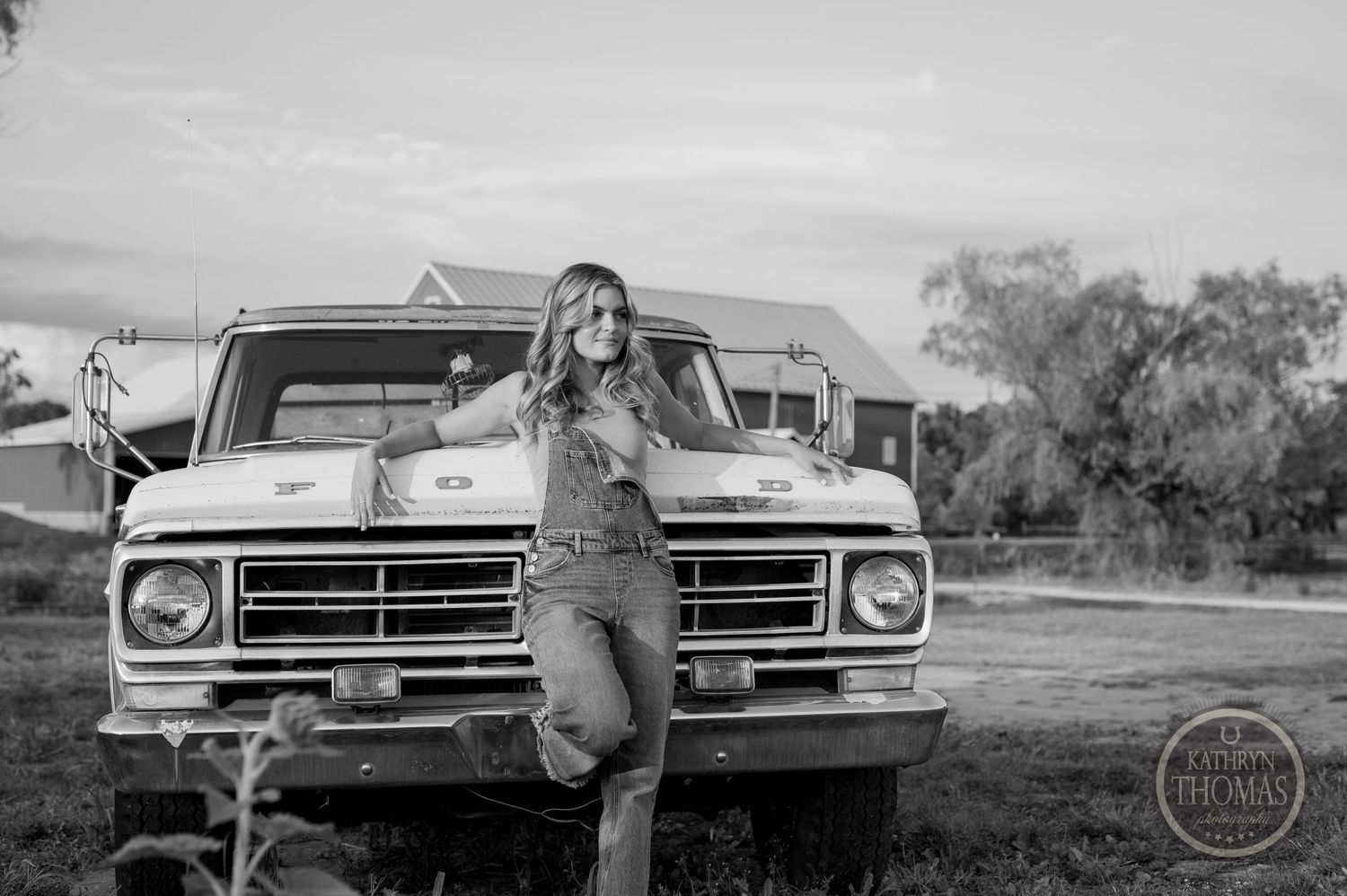A black and white portrait of someone posing with a vintage Ford pickup truck.