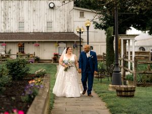 A couple walks together through various garden settings in elegant wedding attire with classic rustic backdrops.