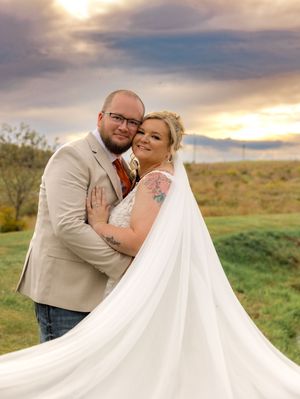 Wedding couple shares intimate moment at sunset in a rustic outdoor setting with dramatic sky overhead.