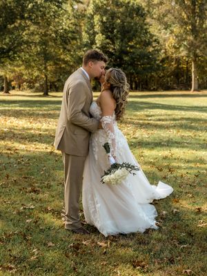 A tender moment between newlyweds in a park setting with golden afternoon light filtering through trees.