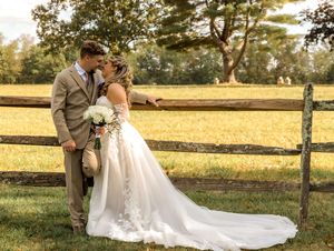 Couple in wedding attire sharing romantic moments at sunset in a rustic farm setting with wooden fences and golden fields.