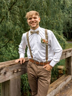 A rustic country wedding photo series with suspenders and brown pants against a wooden fence and natural backdrop.