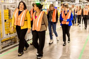 Team members walking through a manufacturing facility while wearing high visibility safety vests.