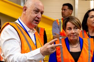 Employees in safety vests having a discussion in an industrial facility.