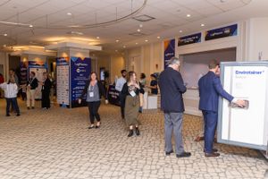 People gathering in a conference center lobby near registration and information displays.
