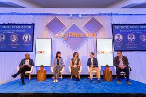 Panel discussion setup at conference with blue lighting and LogiPharma branding on stage.