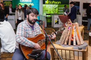 Musician performing with acoustic guitar next to artificial campfire display at event.