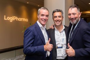 Business professionals posing in front of LogiPharma branded wall.