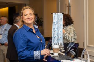 Staff member at registration desk with blue branded display.