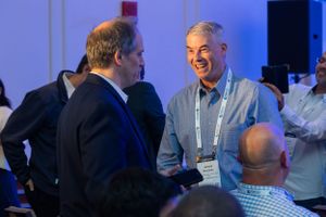 Business professionals engaged in animated conversation at conference.