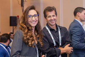 Conference attendees networking and smiling at professional event.