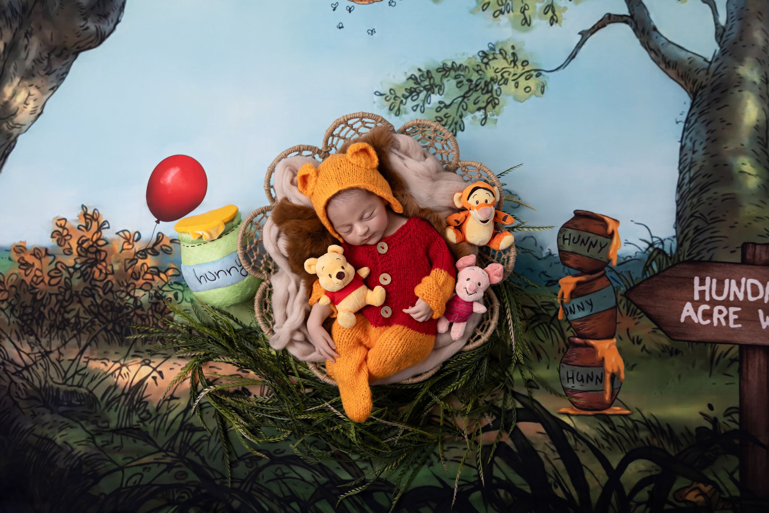 A whimsical display featuring Winnie the Pooh characters in a forest setting with colorful balloons and decor.